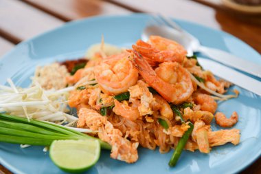 Tayland erişteli Tayland yemeği karides ve yanında da limon, taze soğan ve fasulye filizi.