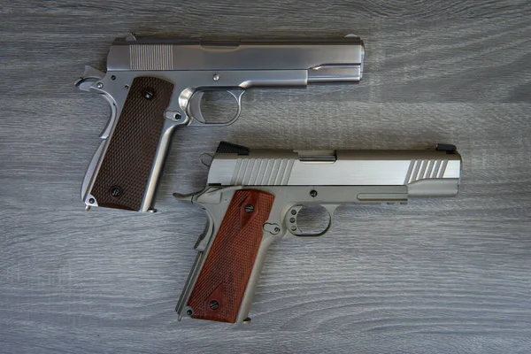 Dwa Pistolety Stali Nierdzewnej Brązowym Uchwytem Jest Drewnianej Podłodze — Zdjęcie stockowe