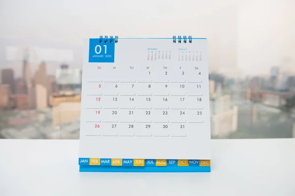 都市の景色を背景にした白いテーブルの上の1月のカレンダー — ストック写真