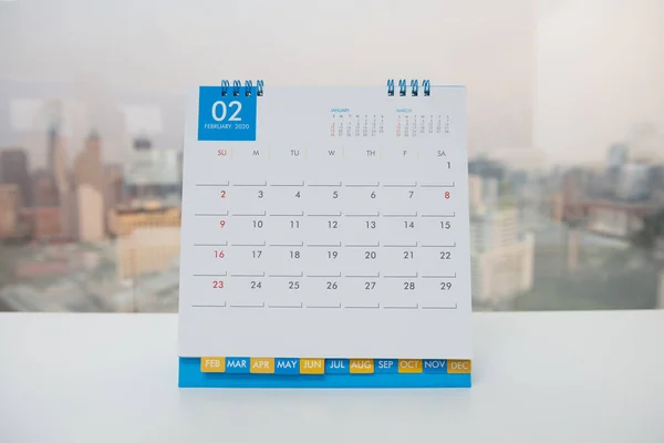 閉じる 都市の景色を背景にした白いテーブルの上の2月のカレンダー — ストック写真