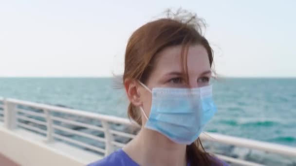 Chica camina en el paseo marítimo en máscara médica — Vídeos de Stock