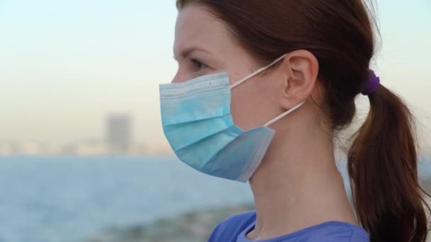 Chica en máscara médica con vista al mar — Vídeos de Stock