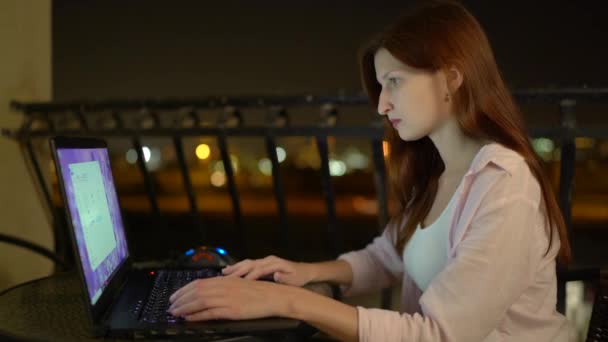 Молодая женщина работает с ноутбуком в ночное время — стоковое видео