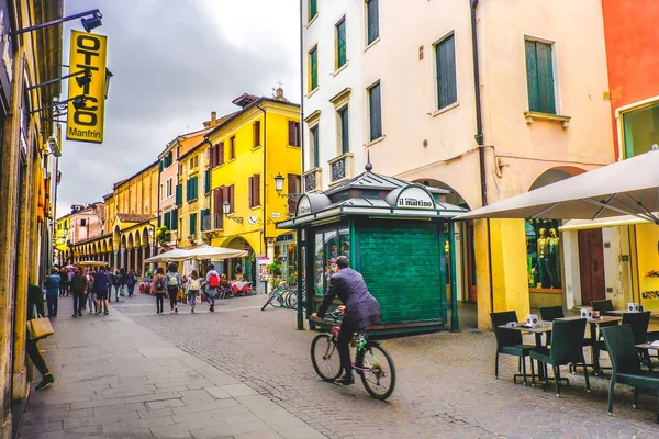 Dagelijks leven in Italië. Een zakenman in fiets overschrijding van een van de centrale wegen van Padua doorgeven door een groene kiosk kiosk van de straat — Stockfoto