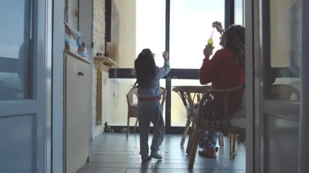 Мама дме мильні бульбашки в домашньому ганку вранці з матір'ю піжами діти дочка разом додому дівчинка — стокове відео