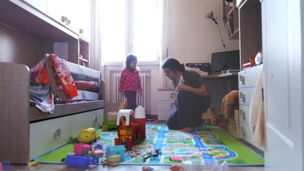 Длинноволосый папа-рокер шутит вокруг с игрушечной гитарой и учит рок и метал-музыкант позирует маленькой дочери в ее комнате — стоковое видео