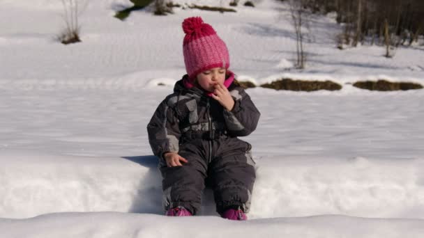 Excursion children baby girl in snowsuit eating snack on mountain snow hike in winter countryside — Stock Video