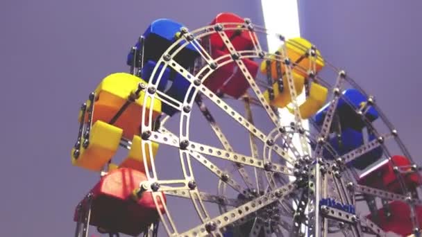 Une roue ferris jouet en métal coloré voir comme vue du bas avec fond violet — Video
