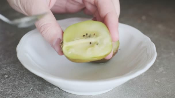 Hand met mes gesneden kiwi fruit helft en neem het met een lepel — Stockvideo