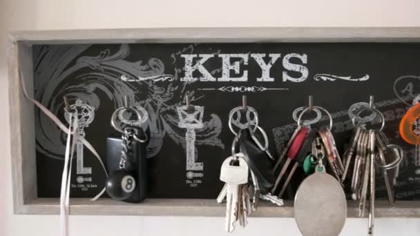 Nyckel hängare horisontell panorering bakgrund av många nyckelringar i semesterhus — Stockvideo