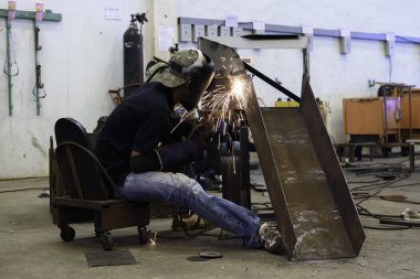 Fabrikada çelik kaynak maskesi giyen işçi