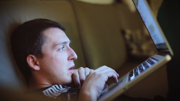 Молодий чоловік, який серфінгує ноутбук в інтернеті вночі близько — стокове відео