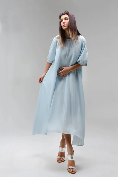 Woman make step in light long blue dress in studio — Stock Photo, Image