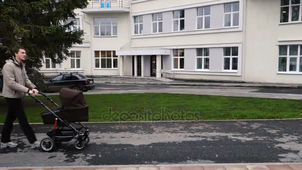 Padre camina con el cochecito caminando por la ciudad — Vídeos de Stock