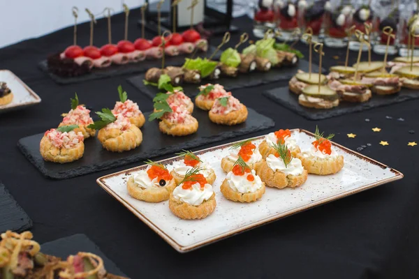 Deliciosos lanches diferentes close-up na mesa preta — Fotografia de Stock