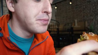 Adam bir restoranda hamburger yakın çekim yemek