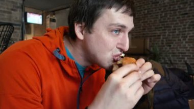 Bir adam fast food café'de bir hamburger yeme