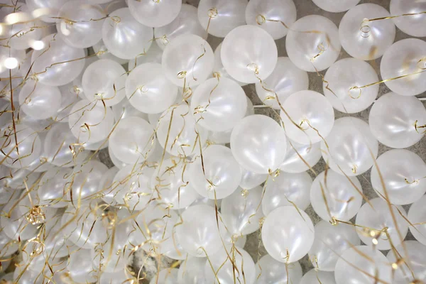 Many white balloons with gold ribbon ceiling