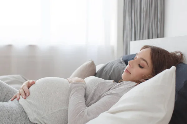 Mulher grávida deitada em uma cama — Fotografia de Stock