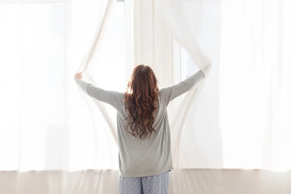 Feminino abre as cortinas pela manhã — Fotografia de Stock