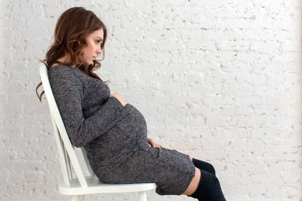 Pregnant female sitting on chair posing — Stock Photo, Image