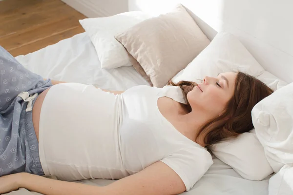 Embarazada sonriente hembra acostada en la cama — Foto de Stock