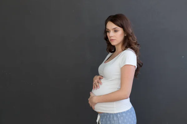 Wanita hamil berpose di latar belakang hitam — Stok Foto
