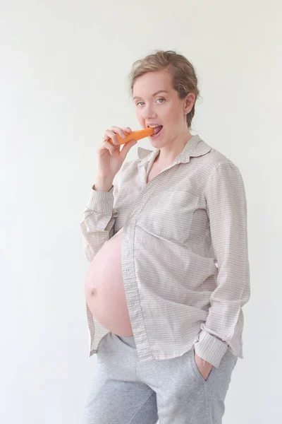 Mulher grávida comendo uma cenoura — Fotografia de Stock