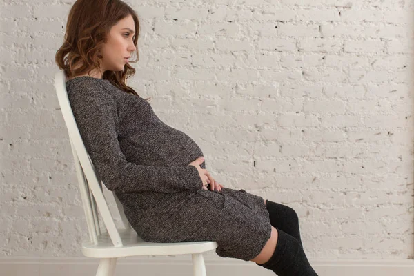 Pregnant female sitting on chair posing