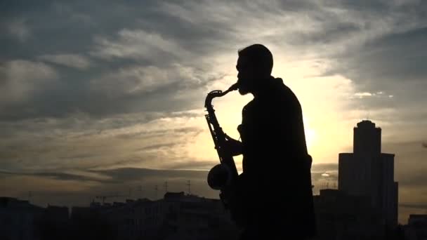 Straat muzikant Speel saxofoon zonsondergang silhouet — Stockvideo