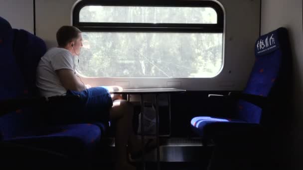 Λυπημένος άνθρωπος ακουστικά από παράθυρο τρένου — Αρχείο Βίντεο