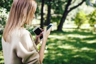 Kadın açık park adlı iki cep telefonu kullanmak