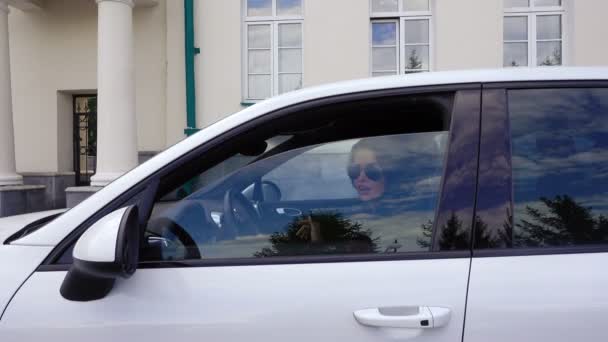 Una mujer abre la ventana del coche sonríe y envía un beso aéreo — Vídeo de stock