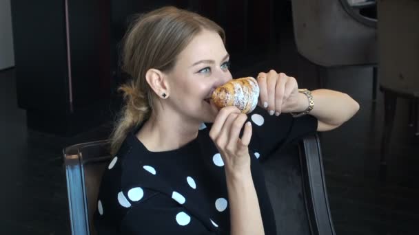 Girl is posing with a croissant to photographer — Stock Video