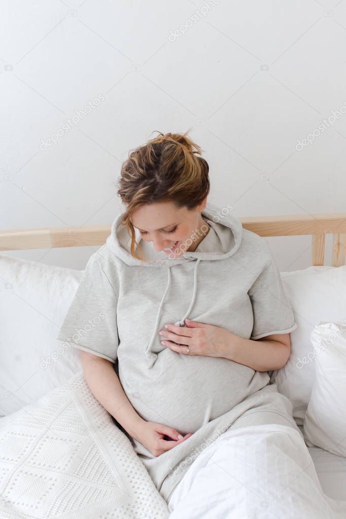 Pregnant smiling female lying on bed