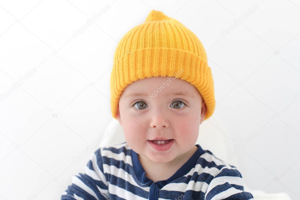 Kid in a yellow hat with two first teeth studio