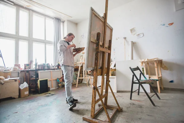 Hombre artista pinta en su taller — Foto de Stock