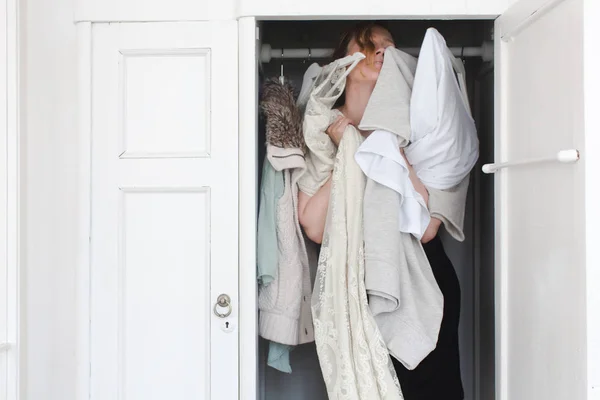 A woman is overwhelmed in closet of messy clothes — Stock Photo, Image