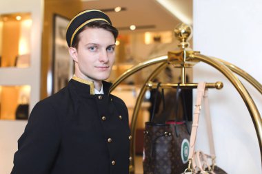 Young man in uniform serving in hotel clipart