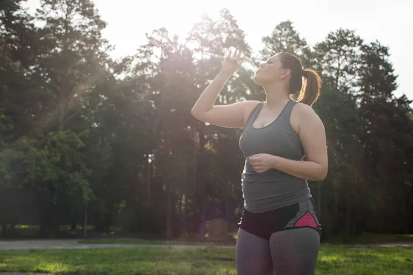 Mulher com excesso de peso bebendo água após o treino — Fotografia de Stock