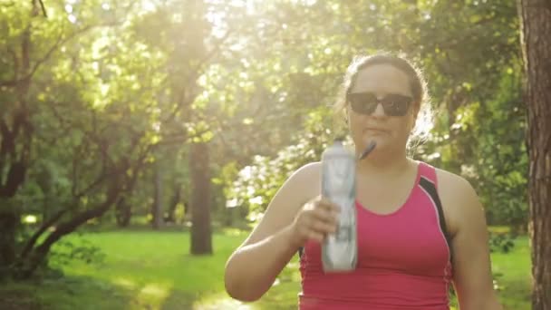 Mujer con sobrepeso bebiendo agua y comienza a correr — Vídeos de Stock