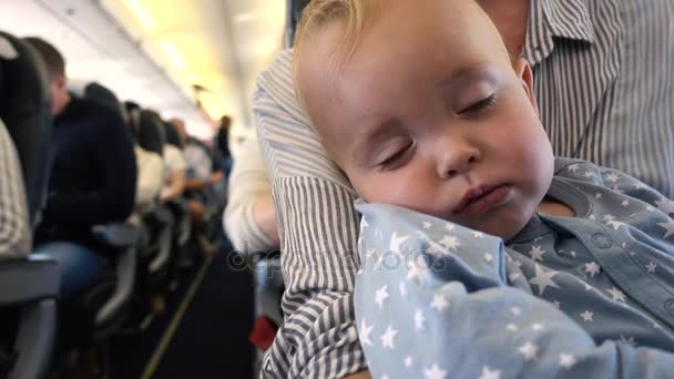 Дитина спить у площині з мамою на руках — стокове відео