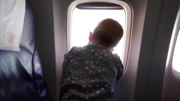 Un bambino di anni guarda fuori dal finestrino di un aeroplano — Video Stock