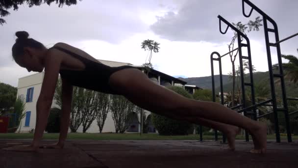 Fit en mooi meisje oefening plank buiten — Stockvideo