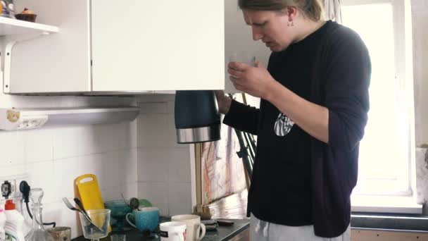 Een man kijkt naar het verdachte water in een waterkoker — Stockvideo