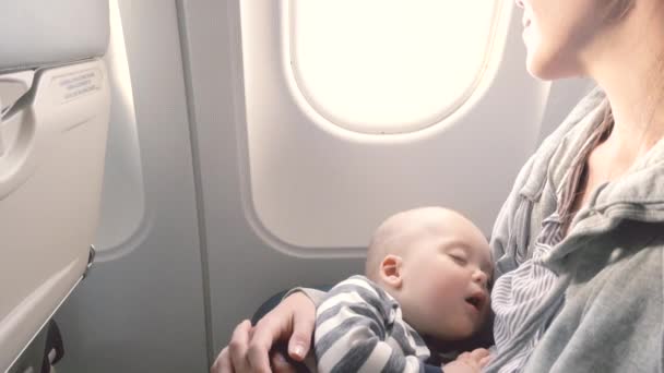 Baby is sleeping in plane with mom in her arms — Stock Video
