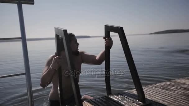 Молодой человек выходит из озера — стоковое видео