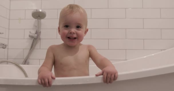 Baby pojke ler och tittar på kameran badrum — Stockvideo