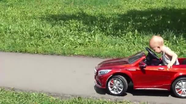Bebé niño está montando un coche de juguete conducido por padre — Vídeo de stock