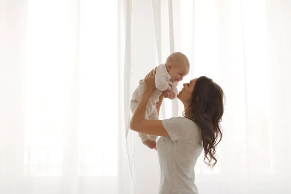 Anya tart egy baba, a karok ablak hátterének — Stock Fotó
